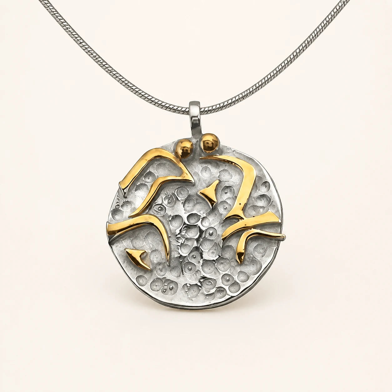 Round hammered silver pendant with raised flowing gold-colored lines