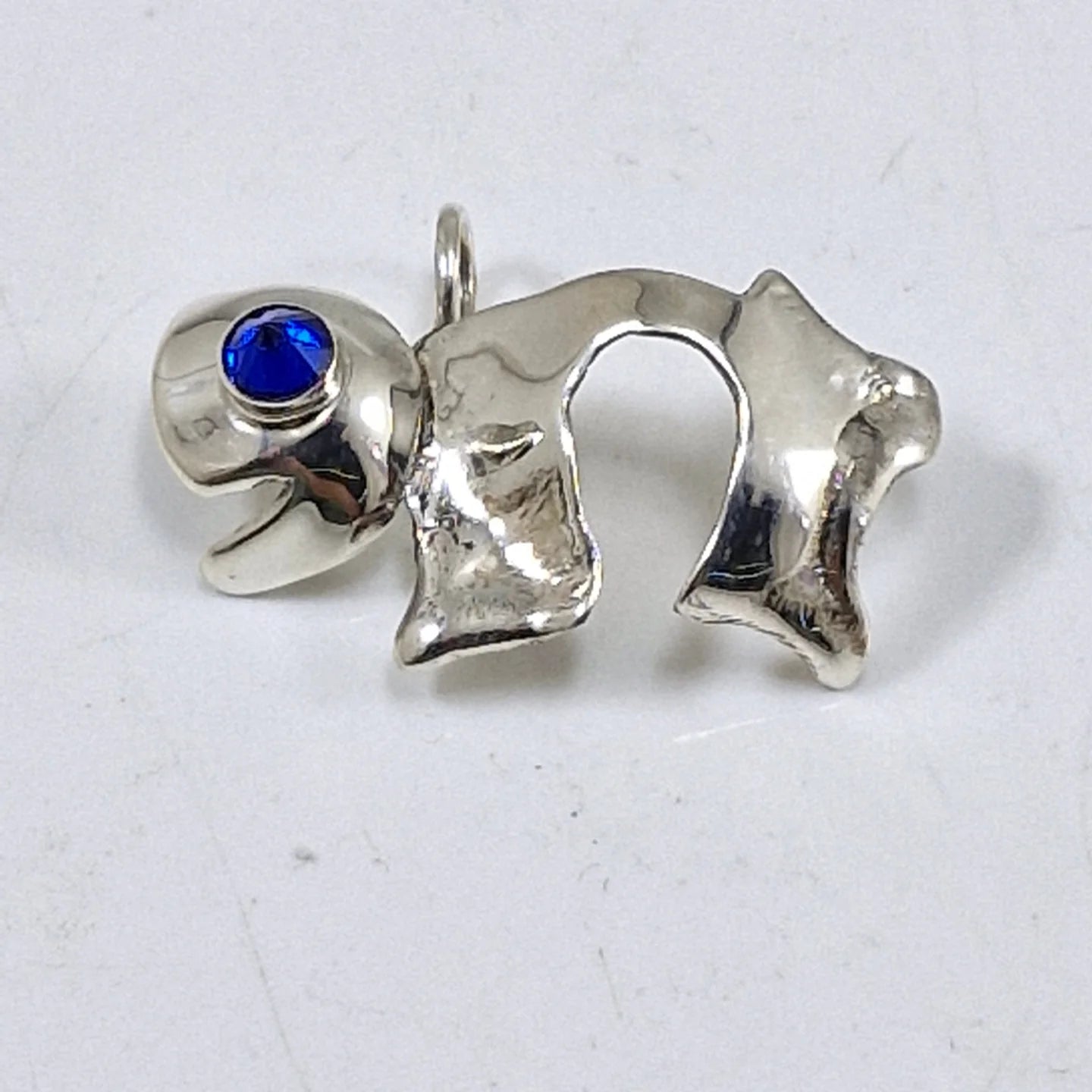 Polished silver Chai pendant with a round blue opal accent