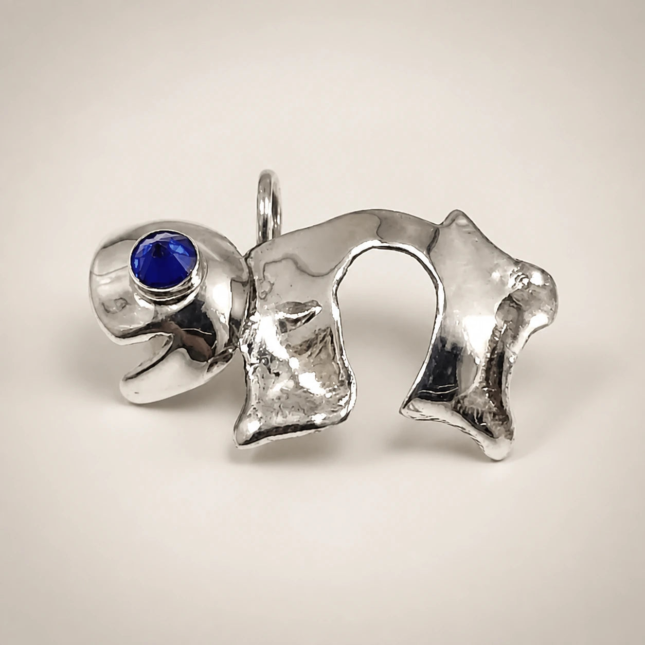 Sculptural silver elephant pendant with a cobalt-blue stone