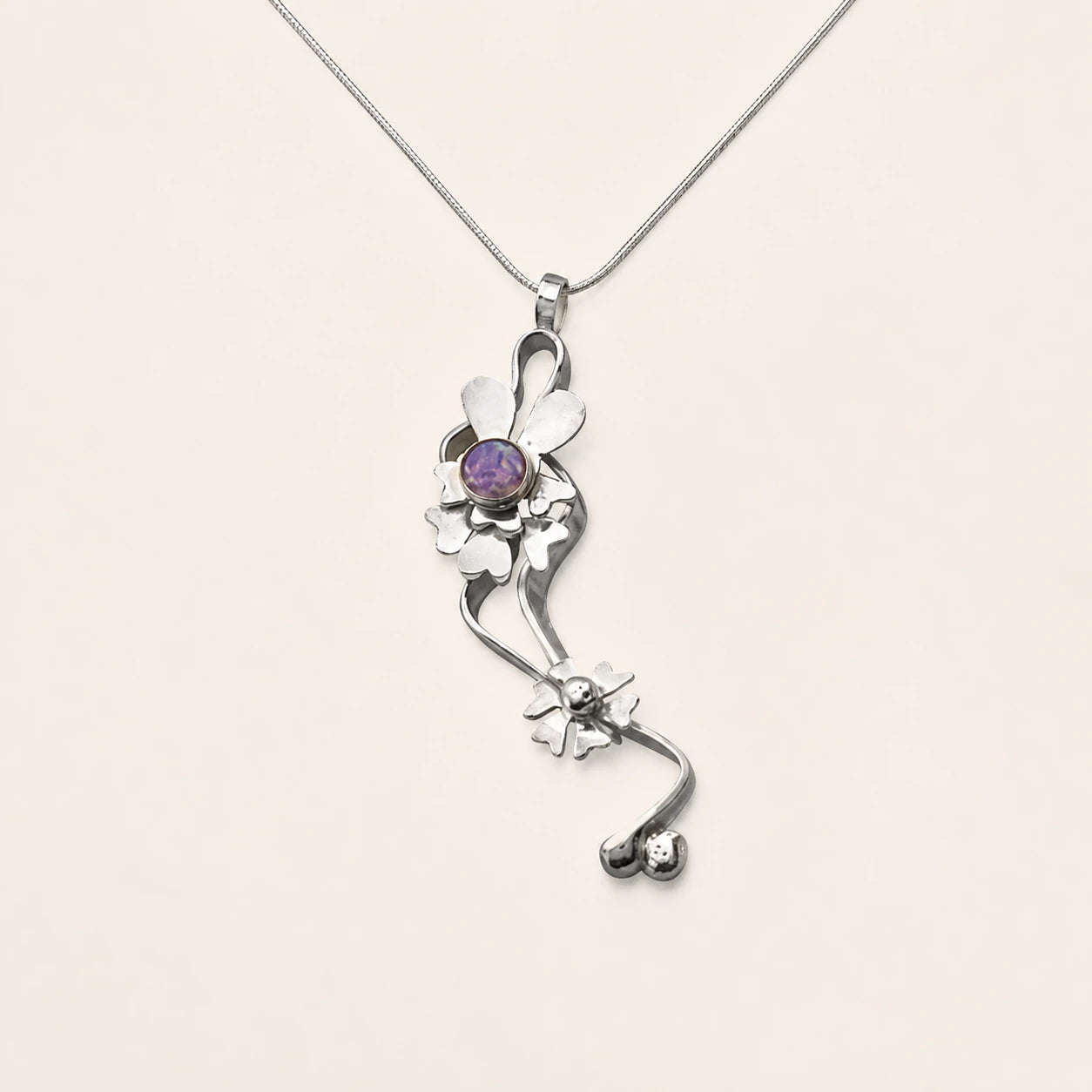 Long sculptural silver floral pendant with a purple center stone
