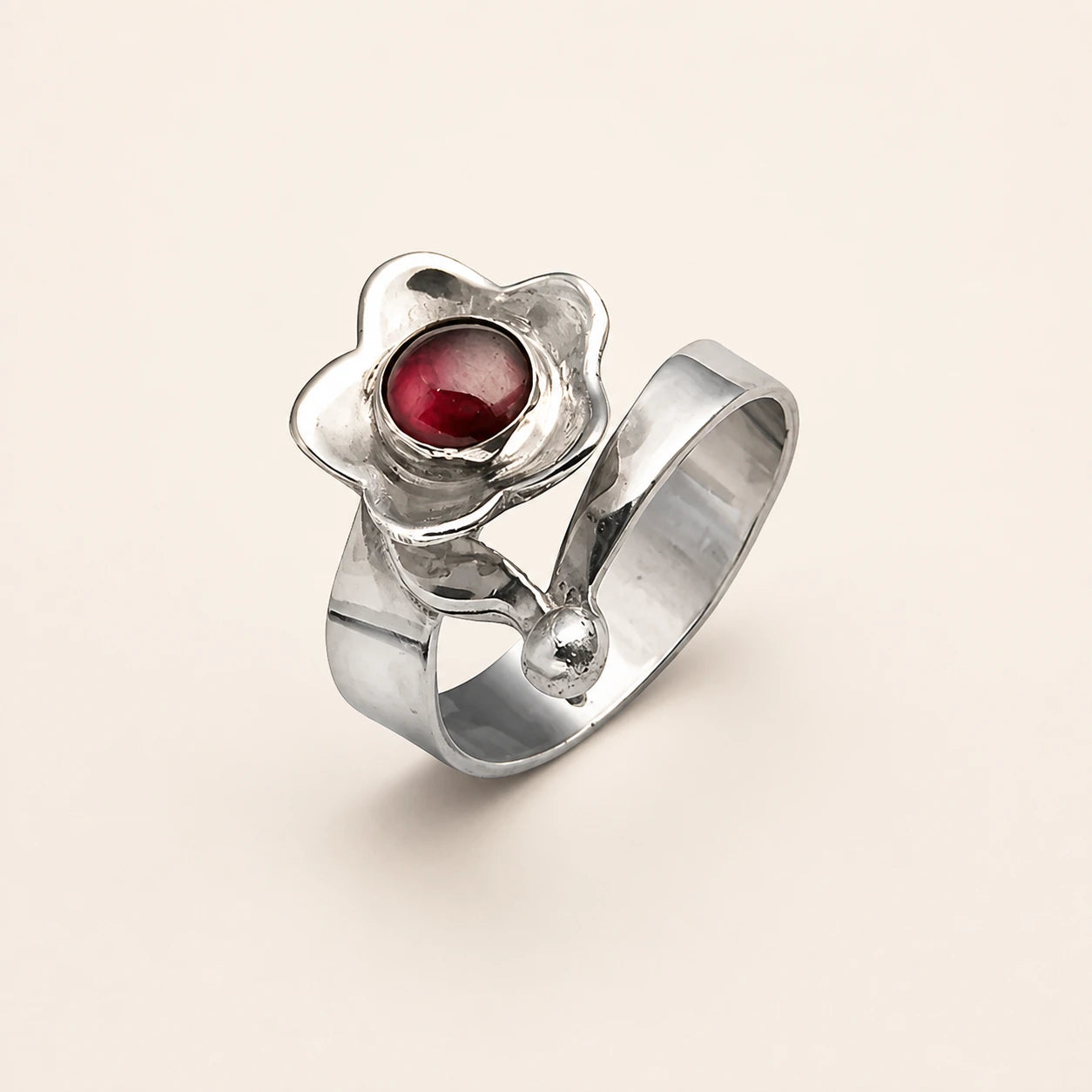 Sculptural silver flower ring with a deep red center stone